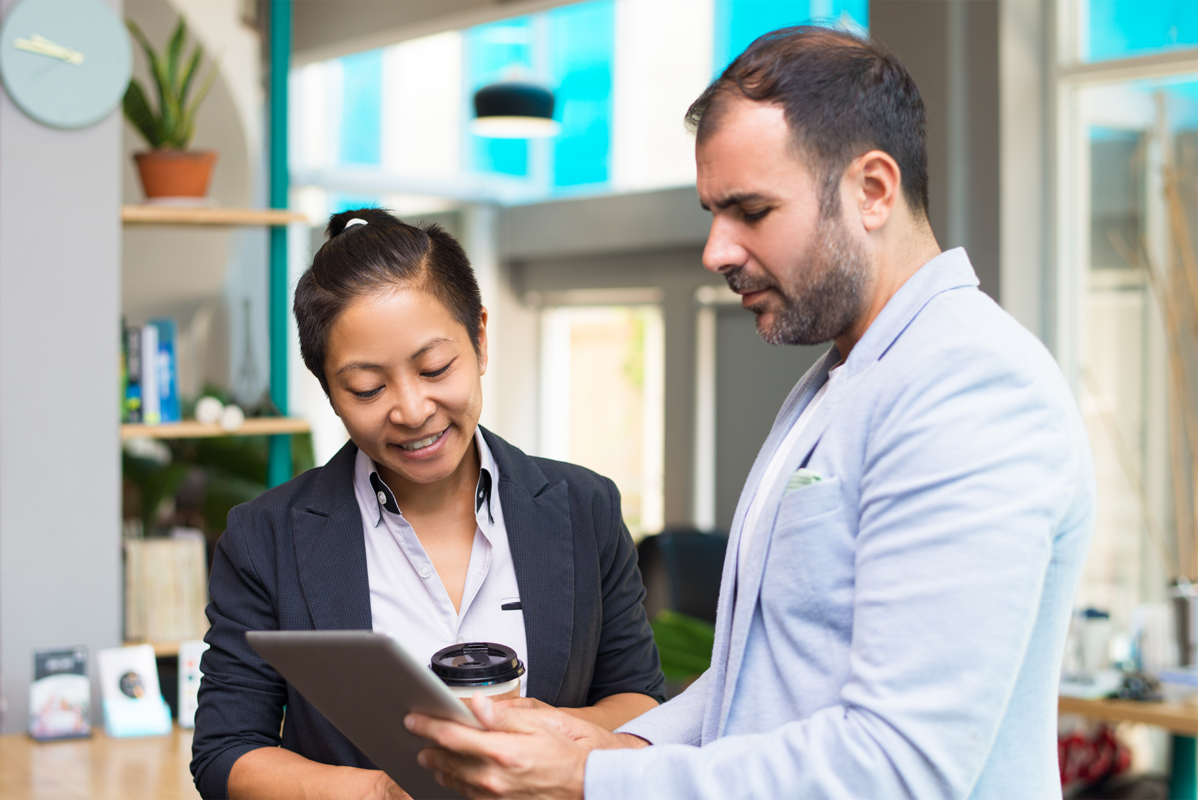 Two business professionals reviewing payment data on a tablet, representing unified B2B payment solutions with Hyfin